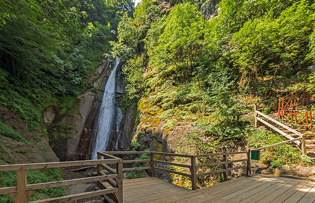 Smolare Waterfalls deep within a forest with a wooden bridge to enjoy the view